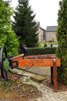 a bench with a sign for a garden with flowers at Gîtes de Chevémont in Plombières