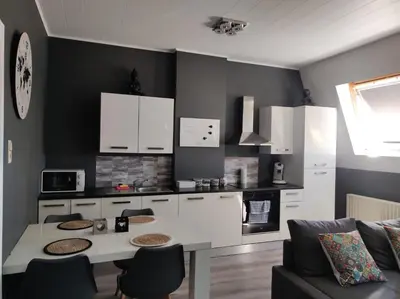 a kitchen with white cabinets and a table with chairs at Escale in Liège