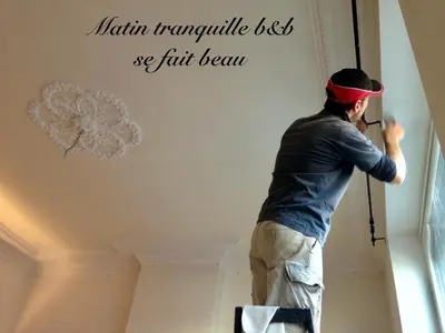 a man painting a wall with the words north removable best we full beam at B&B Matin Tranquille in Liège