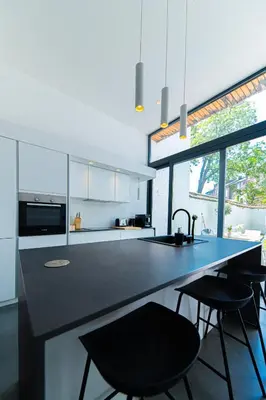 a kitchen with a black counter and some chairs at Garden Guillemins Station in Liège