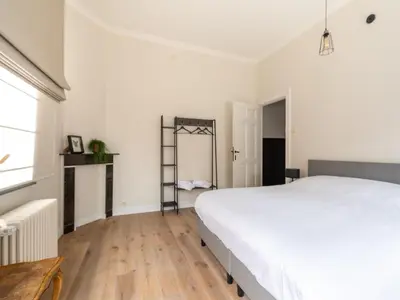 a bedroom with a large white bed and wooden floors at Scenic villa in Borgloon with garden in Borgloon