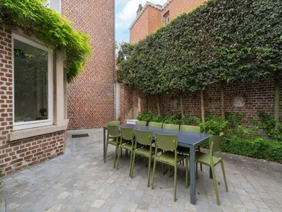 a table and chairs in front of a brick building at Scenic villa in Borgloon with garden in Borgloon