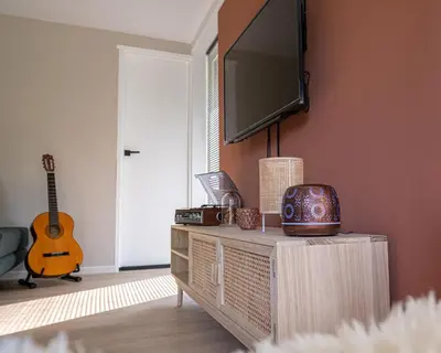 a living room with a tv on a wall with a guitar at 't Bunga huiske in Lanaken
