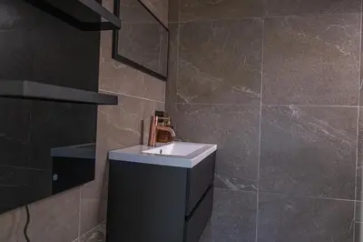 a bathroom with a sink and a tiled wall at 't Bunga huiske in Lanaken