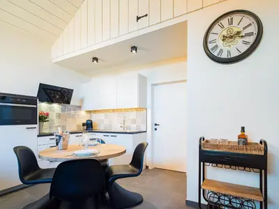 a kitchen with a table and a clock on a wall at Welldone Resort / Cozy Wine in Nieuwerkerken