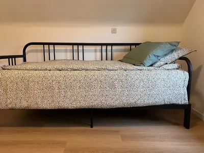 a bed with a black frame and two pillows on it at De Bovenbuur in Lummen