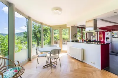 a kitchen with a table and chairs and windows at Côté cour, côté source chambre d'hôtes in Chaudfontaine