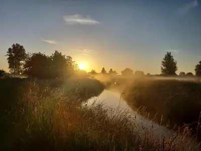 a misty sunrise over a river in a field at Rustig gelegen chalet Solvo met terras aan het water in Geel