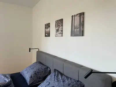 a bed with two pillows and three pictures on the wall at Casa 47 in Eupen