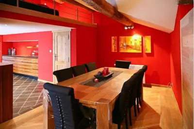 a dining room with a wooden table and red walls at Jacuzzi - BBq - Jardin - Garden Lodge - Le Tulipier in Olne
