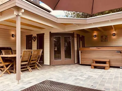 a patio with a table and chairs and an umbrella at Jacuzzi - BBq - Jardin - Garden Lodge - Le Tulipier in Olne