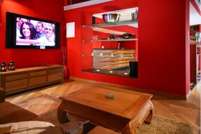 a living room with red walls and a flat screen tv at Jacuzzi - BBq - Jardin - Garden Lodge - Le Tulipier in Olne