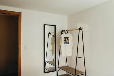 a mirror on a wall with a white shirt hanging at L'Orée du Bois by WelcHome in Verviers