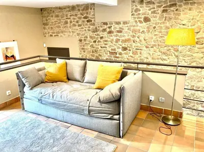 a couch in a living room with a stone wall at Le Val du Cossart by WelcHome in Verviers