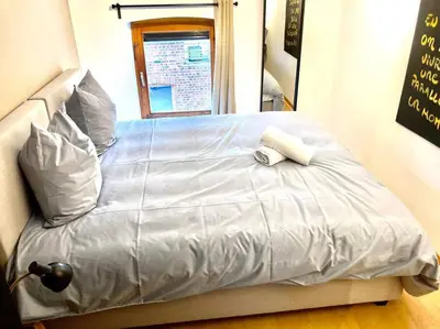 a bed with a white blanket and pillows on it at Le Val du Cossart by WelcHome in Verviers