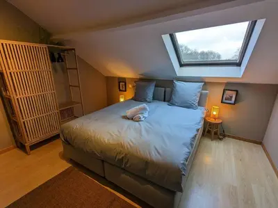 a bedroom with a large bed with a skylight at Le Voisin du Pré by WelcHome in Verviers