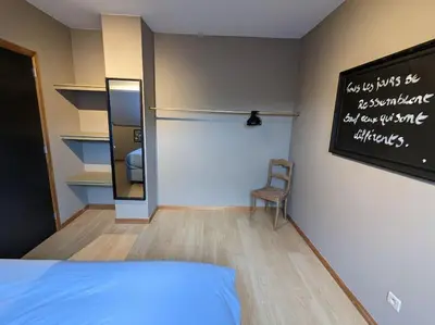 a bedroom with a bed and a chalkboard on the wall at Le Voisin du Pré by WelcHome in Verviers