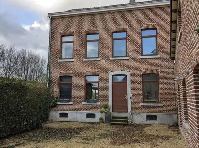 a brick building with a red door and a porch at Le Voisin du Pré by WelcHome in Verviers