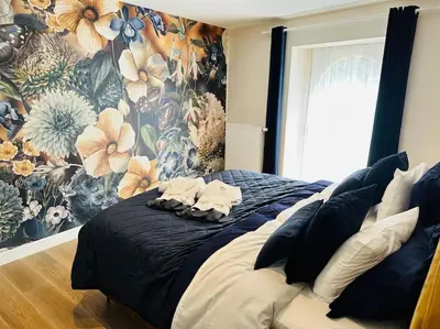 a bedroom with a large bed with a floral wallpaper at Jacuzzi - Sauna - BBq - Jardin - Garden Lodge - Myosotis in Olne