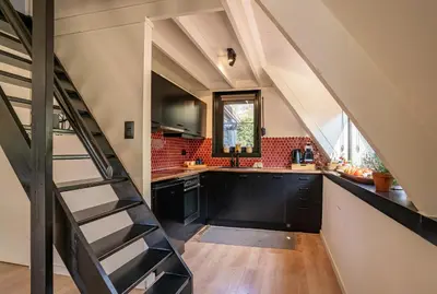 an attic kitchen with black cabinets and a staircase at Boshuisje Rekem - Topo in Lanaken