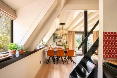 a kitchen and dining room with a staircase and orange chairs at Boshuisje Rekem - Topo in Lanaken