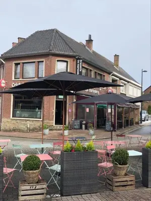 a cafe with tables and umbrellas in front of a building at Homestay La Montagne des Coeurs in Eigenbilzen