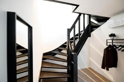 a black staircase in a white room with a mirror at Bij de secretaris in Kanne