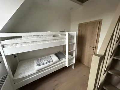 a bunk bed with white bunk beds in a room at La Forteresse in Borgloon