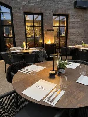 a wooden table in a restaurant with tables and chairs at La Forteresse in Borgloon