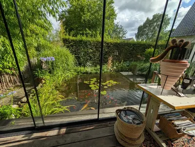 a view of a garden from a window with a pond at De Tuinkamer in Lanaken