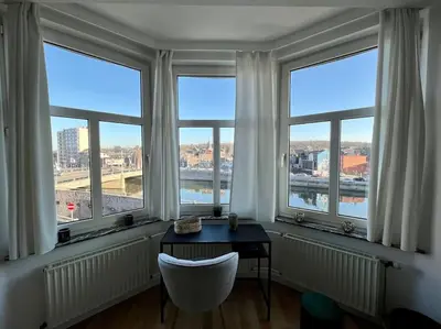 a room with a desk in front of windows at Bellevue - Grand appartement pour 5 sur les quais de la Meuse in Liège