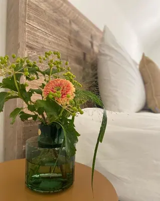 a vase with flowers on a table next to a bed at Vakantiewoning 't Hovenshuis in Kinrooi