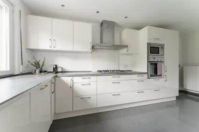 a white kitchen with white cabinets and appliances at Vakantiewoning 't Hovenshuis in Kinrooi