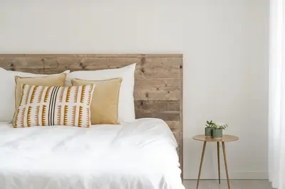 a bed with white sheets and pillows and a table at Vakantiewoning 't Hovenshuis in Kinrooi