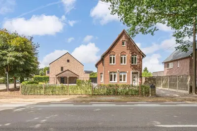 a brick house with a fence next to a street at Vakantiewoning 't Hovenshuis in Kinrooi