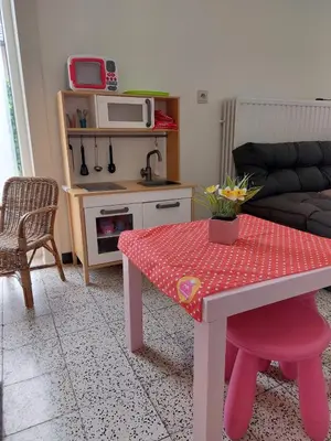 a living room with a pink table and a kitchen at Vakantiewoning De Papendaler in Zutendaal