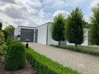 a house with a garage and a brick driveway at Vakantiewoning De Papendaler in Zutendaal