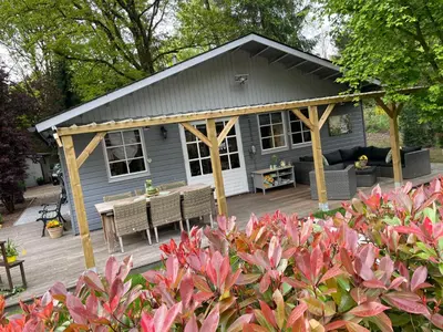 a gray house with a table and a bench on a deck at Chalet Sint-Hubertus Du Bois in Zutendaal