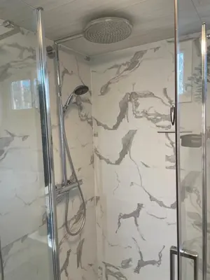 a shower in a bathroom with a marble wall at Chalet Sint-Hubertus Du Bois in Zutendaal