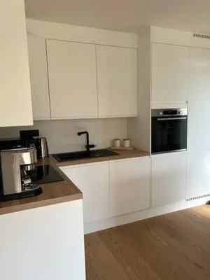 a kitchen with white cabinets and a black appliance at Le Chalet du Pays de Herve in Herve