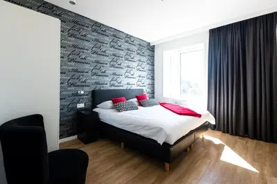 a bedroom with a brick wall and a bed with red pillows at Appart'hotel Urban Lodge in Chaudfontaine