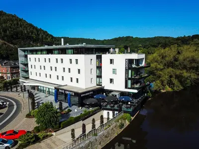 a large white building next to a body of water at Appart'hotel Urban Lodge in Chaudfontaine