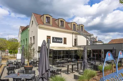 a restaurant with tables and umbrellas in front of a building at Hotel de Boskar Houthalen in Houthalen-Helchteren