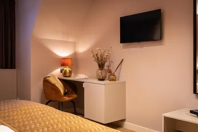 a bedroom with a desk and a television on a wall at Hotel de Boskar Houthalen in Houthalen-Helchteren