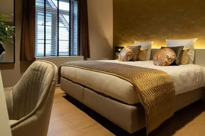 a bedroom with a bed with a chair and a window at Hotel de Boskar Houthalen in Houthalen-Helchteren
