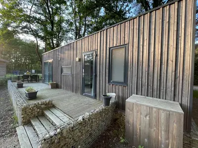 a small wooden house with a wooden deck at Chalet Het Edelhert in Zutendaal