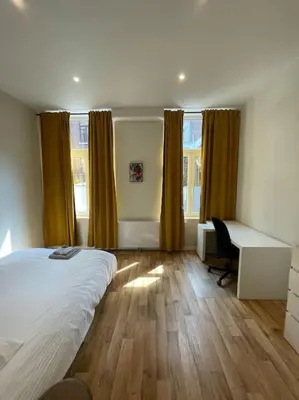 a bedroom with a bed and a desk and window at Maison 4 chambres avec jardin in Liège