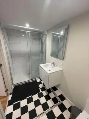 a bathroom with a sink and a shower and a checkered floor at Maison 4 chambres avec jardin in Liège