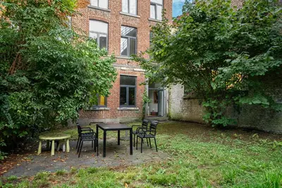 a table and chairs in front of a brick building at Maison 4 chambres avec jardin in Liège