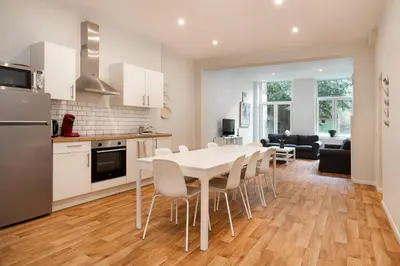 a kitchen and living room with a white table and chairs at Maison 4 chambres avec jardin in Liège